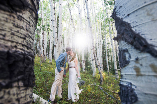 bride and groom kiss under aspens