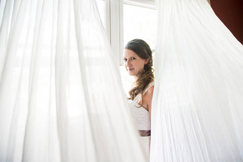 bride peering from behind white curtains