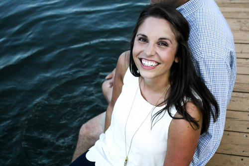 smiling couple dangling feet over dock into water